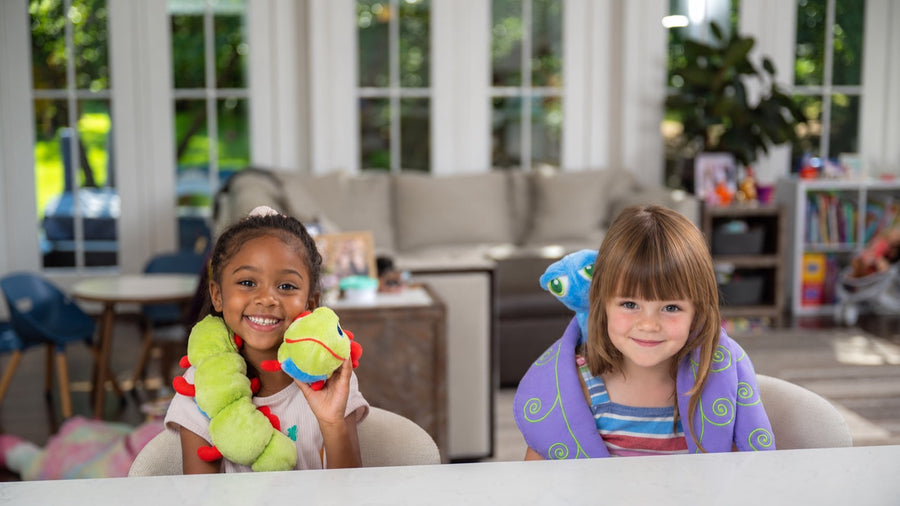 Two children in pyjamas on a family-room sofa in the evening, one holding Flutter.