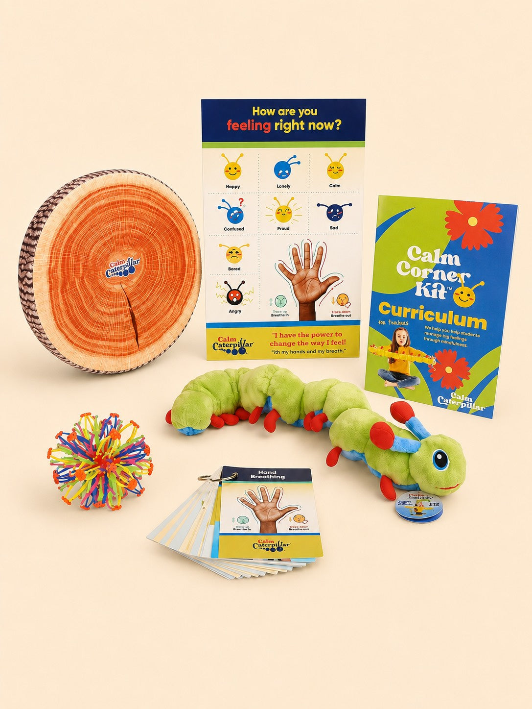 The Calm Corner Kit laid out: a tree-stump sitting cushion, the How are you feeling right now poster, the Calm Corner Kit Curriculum for teachers, Calmee the caterpillar plush, an expandable breathing ball, and a ring of hand-breathing cards