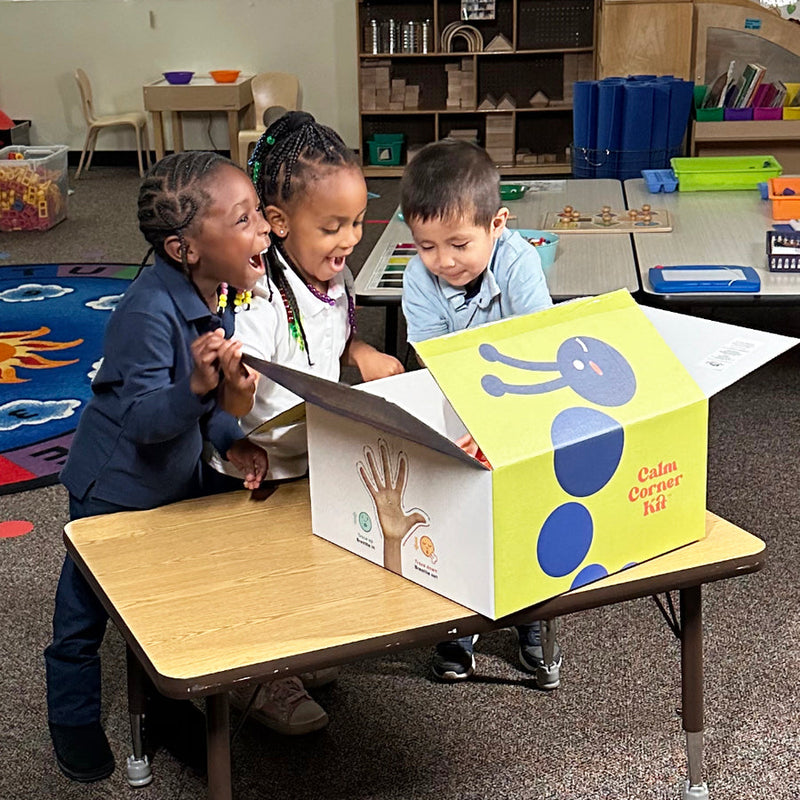 Image showing 3 kids looking inside the Calm Corner Kit box, which contains tools to help calm down kids.