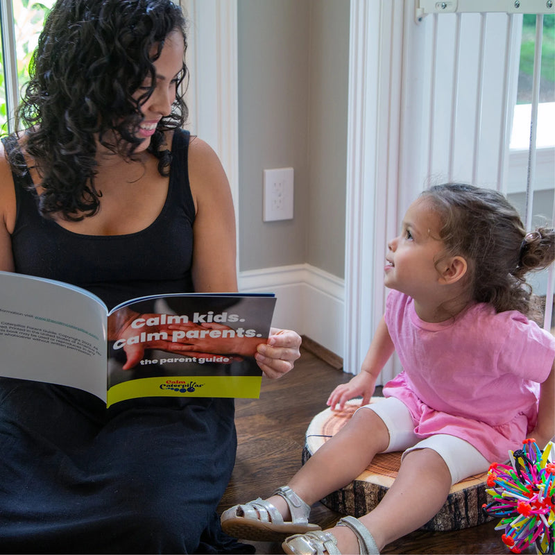 Image showing a parent reading the parent field guide from the Calm Corner Kit, which is one of 5 tools for calming down kids. The parent field guide is an easy-access reference point to remind yourself of how to apply these calming methods.