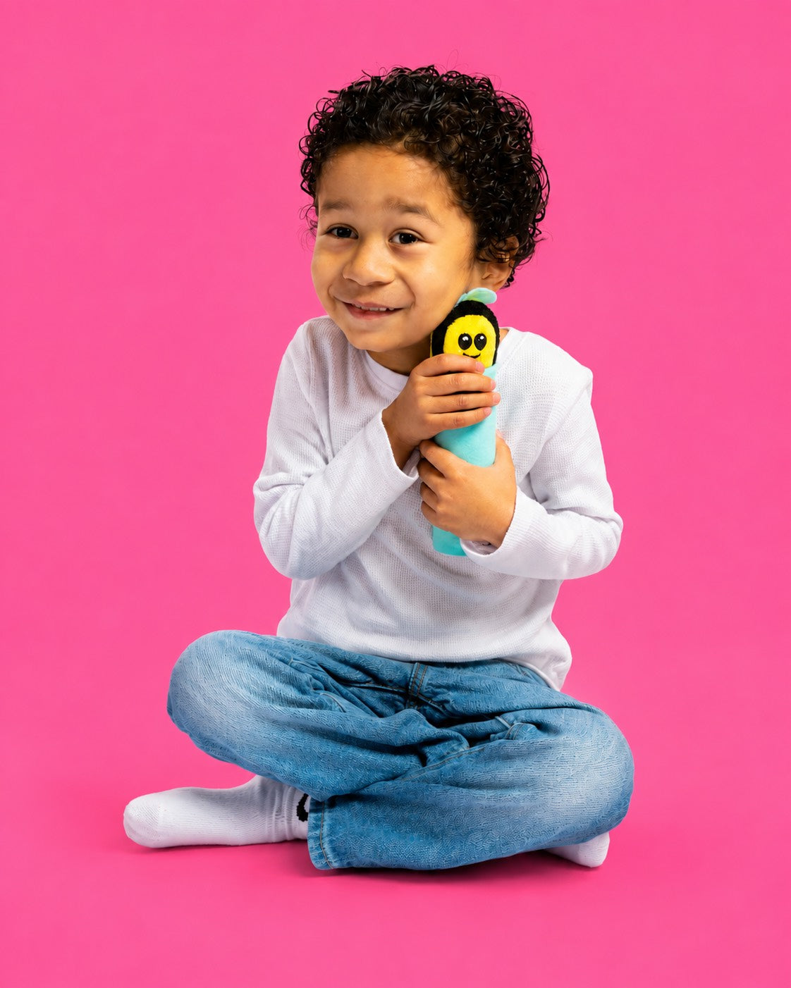 A child holding Buzzee the Bee against a pink background