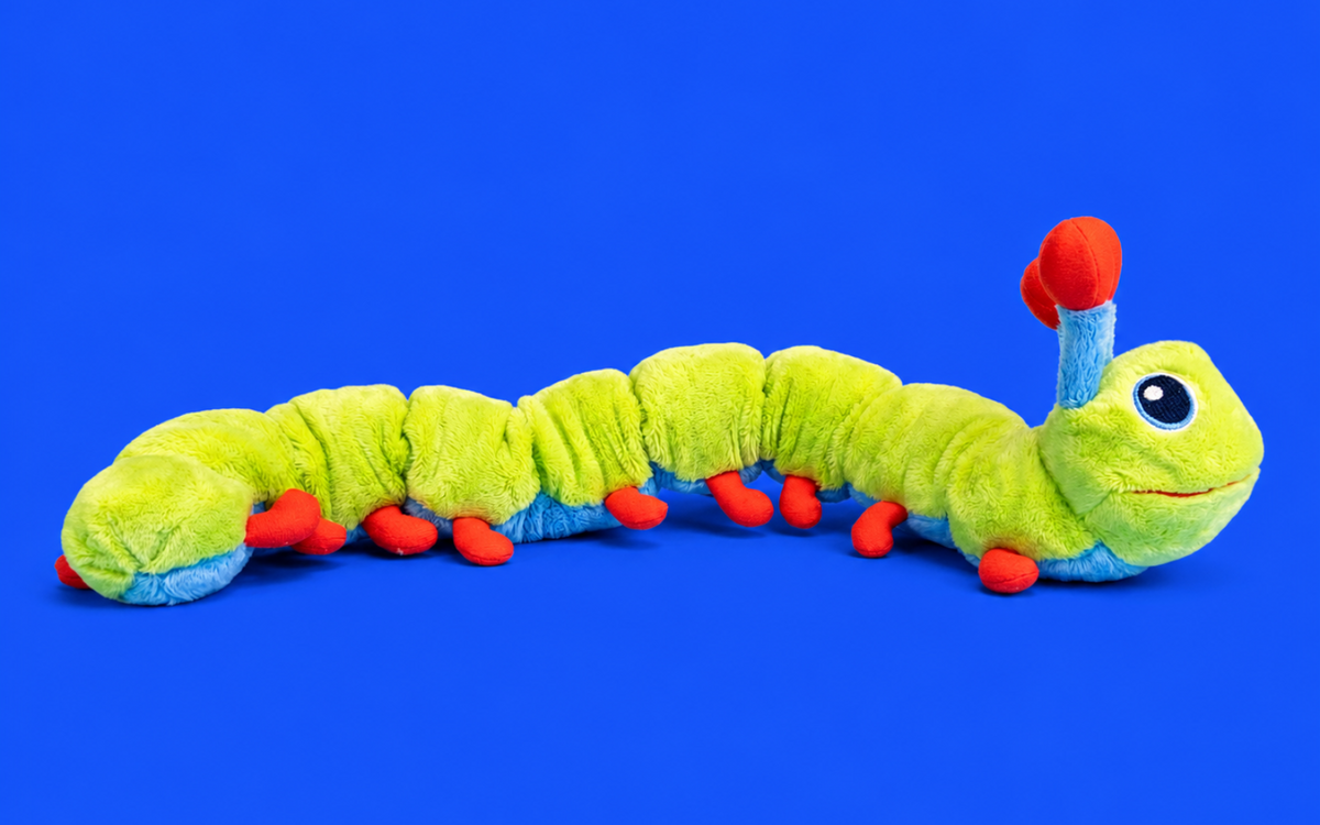 Calmee the Caterpillar plush stretched out on a blue background, antennae raised