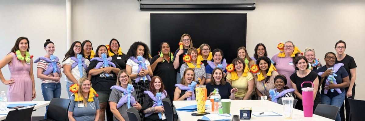 A room of teachers holding Calmee, Flutter, and Rory plush tools after a Calm Caterpillar training session.