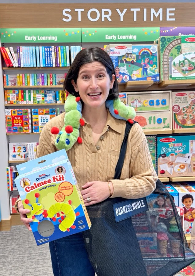 Sarah Habib holding a Calmee Kit box in the Storytime section of a Barnes & Noble, with Calmee around her neck.