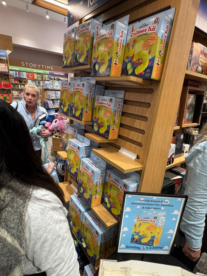 A bookstore display of Calmee Kits with shoppers browsing beside it.