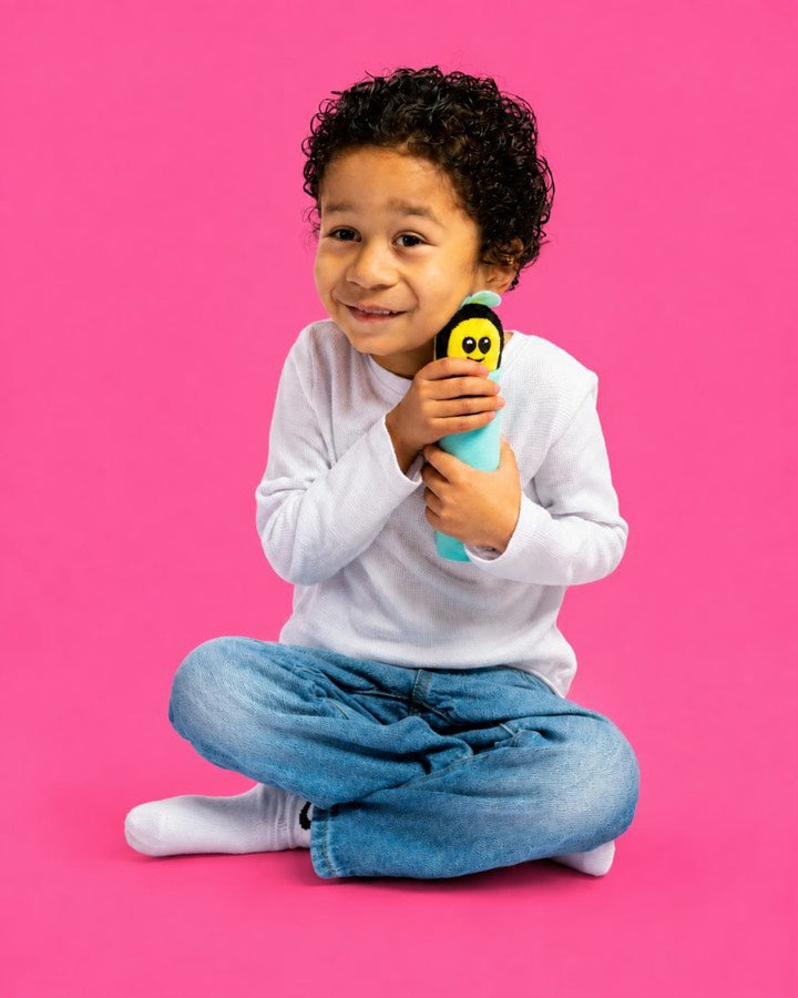 A child sitting cross-legged holding Buzzee against their chest.