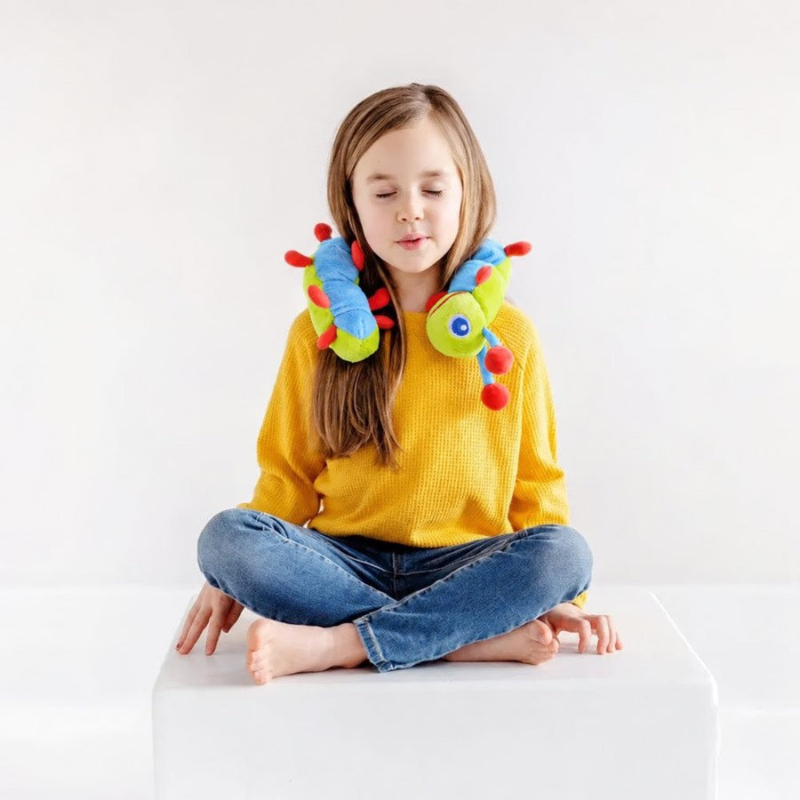 A child sitting cross-legged with Calmee draped across their shoulders, eyes closed, breathing out.